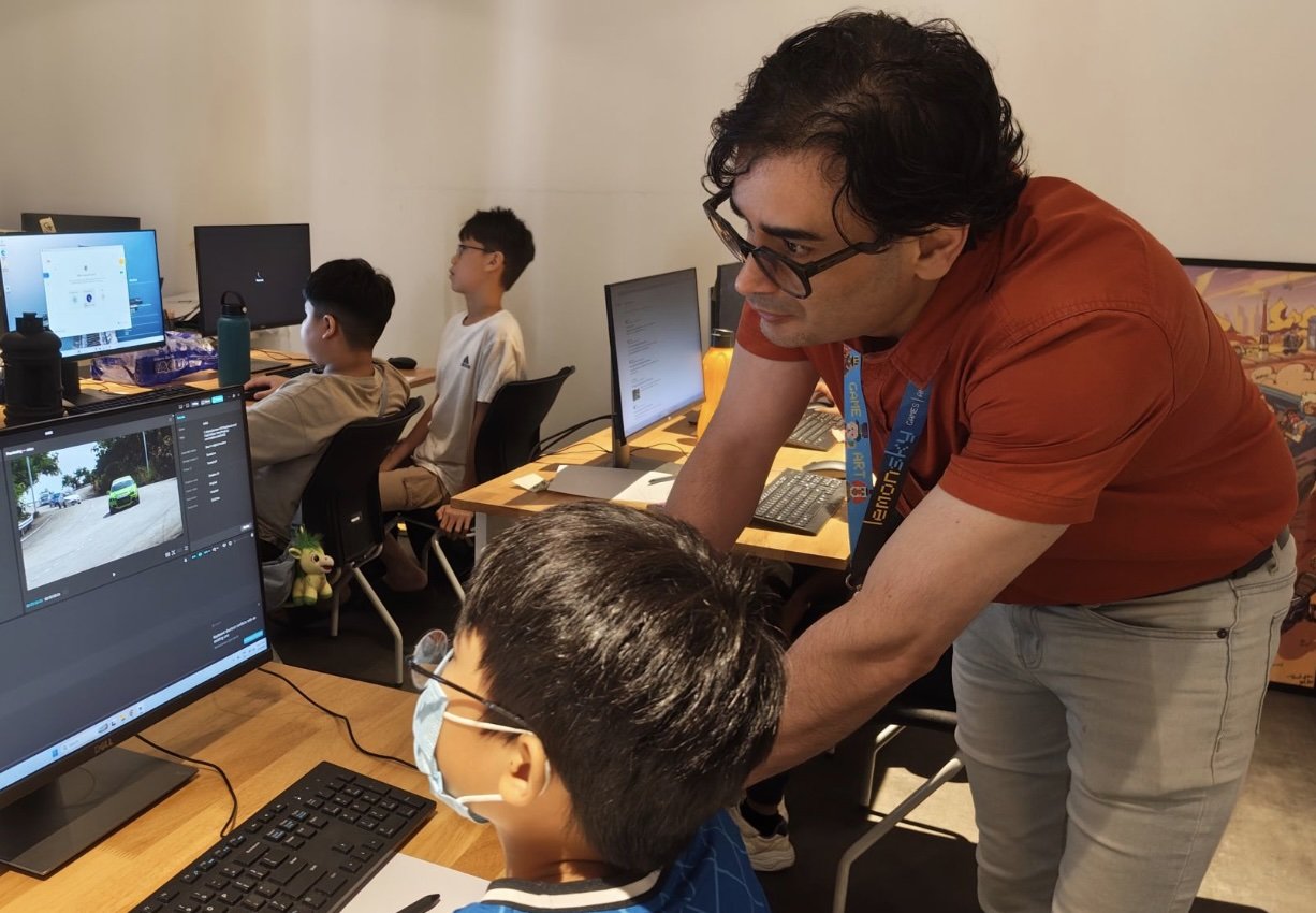 A mentor guiding young students through AI-powered creative projects at the studio